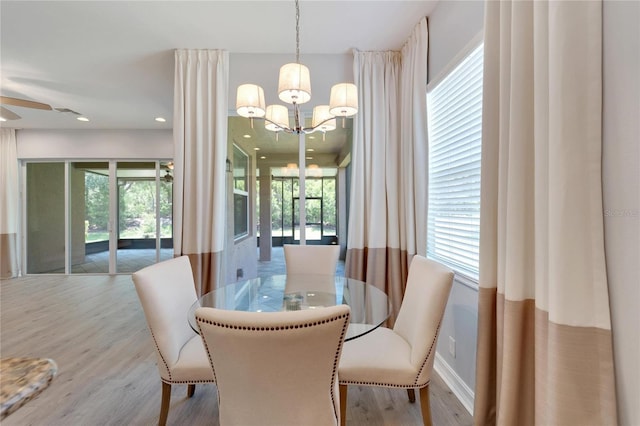 dining space featuring ceiling fan with notable chandelier and light wood-type flooring