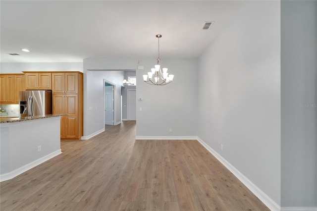 kitchen with decorative light fixtures, light hardwood / wood-style floors, stainless steel refrigerator with ice dispenser, light stone countertops, and light brown cabinets