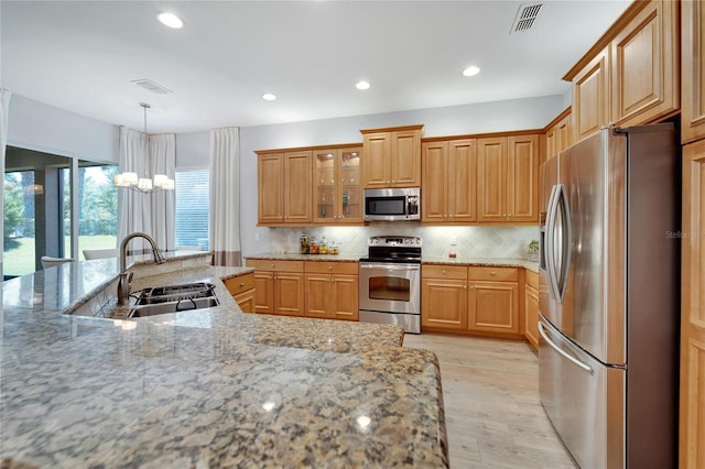 kitchen with decorative light fixtures, sink, decorative backsplash, stainless steel appliances, and light stone countertops