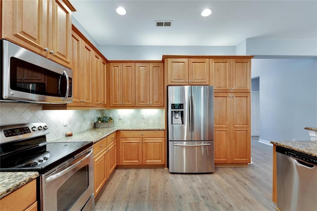 kitchen featuring light stone countertops, appliances with stainless steel finishes, backsplash, and light hardwood / wood-style floors