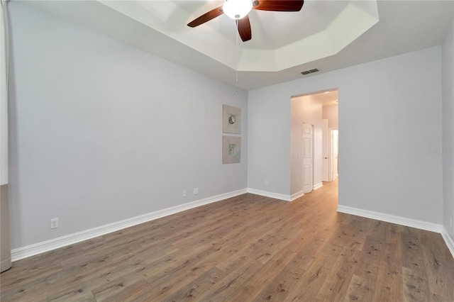 unfurnished room with hardwood / wood-style flooring, ceiling fan, and a raised ceiling