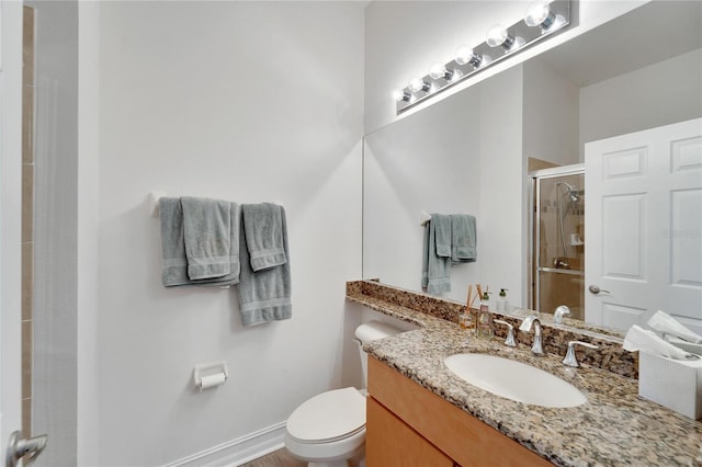 bathroom with vanity, a shower with door, and toilet