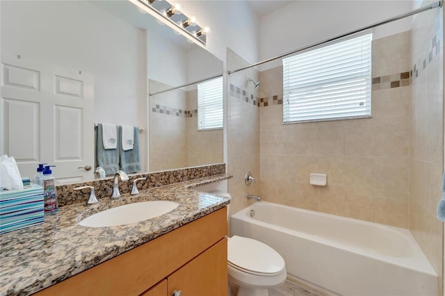 full bathroom with tiled shower / bath, vanity, and toilet