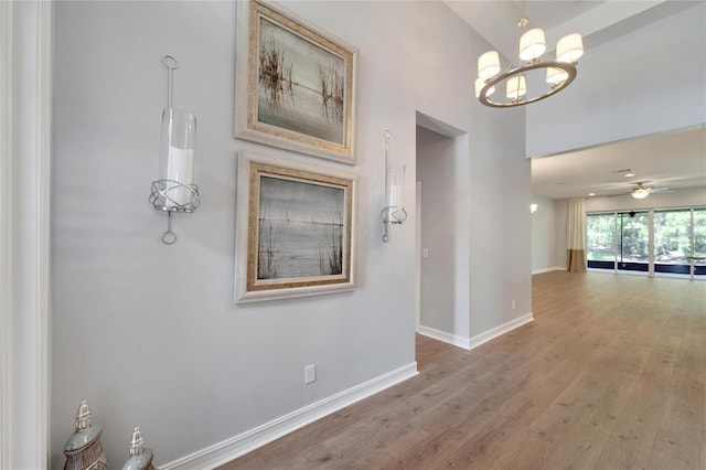 hall featuring wood-type flooring and a chandelier