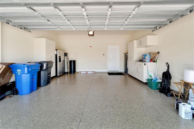 garage with a garage door opener and stainless steel refrigerator with ice dispenser