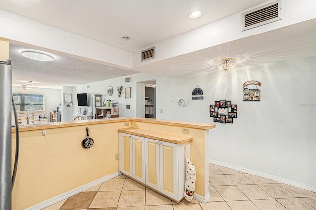 kitchen with light tile patterned floors, a textured ceiling, and kitchen peninsula