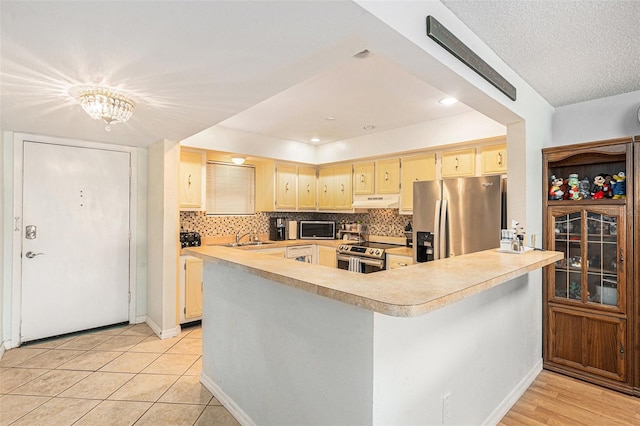 kitchen with backsplash, stainless steel appliances, and kitchen peninsula