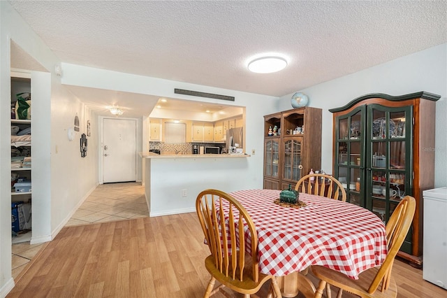 dining room featuring washer / dryer, light hardwood / wood-style floors, and a textured ceiling