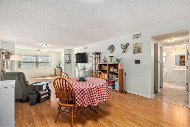 dining area with ceiling fan, light hardwood / wood-style floors, and a textured ceiling