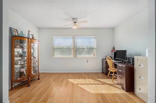 home office with ceiling fan, light hardwood / wood-style flooring, and a textured ceiling