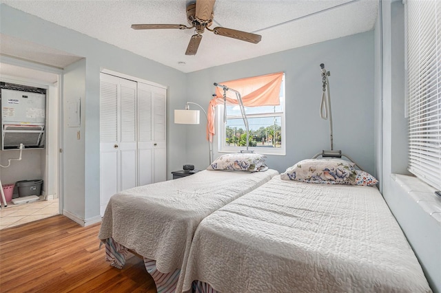 bedroom featuring wood-type flooring, ceiling fan, a textured ceiling, and a closet