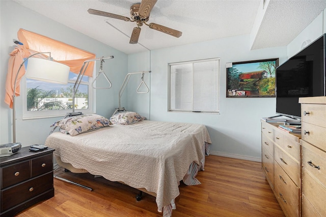 bedroom featuring a textured ceiling, ceiling fan, and light wood-type flooring