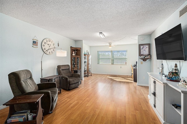 living room featuring a textured ceiling, ceiling fan, and light hardwood / wood-style flooring