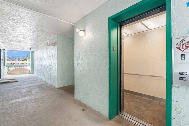 corridor featuring elevator and concrete floors