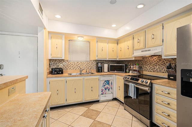 kitchen with sink, light tile patterned floors, stainless steel appliances, and decorative backsplash