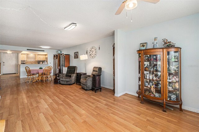 sitting room with ceiling fan, light hardwood / wood-style flooring, and a textured ceiling