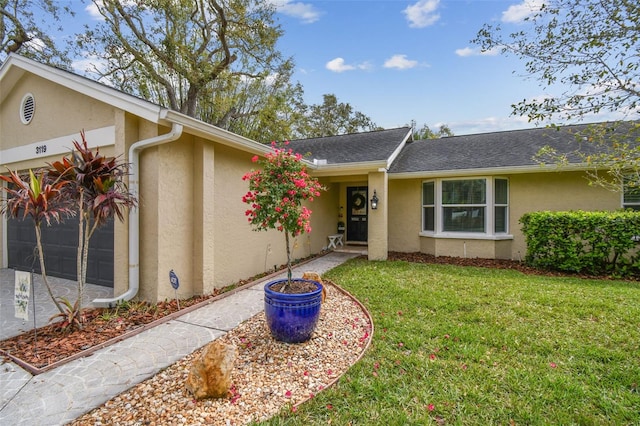 view of front of house featuring an attached garage, driveway, a front yard, and stucco siding