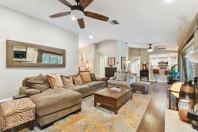 living room featuring baseboards, visible vents, hardwood / wood-style flooring, ceiling fan, and vaulted ceiling