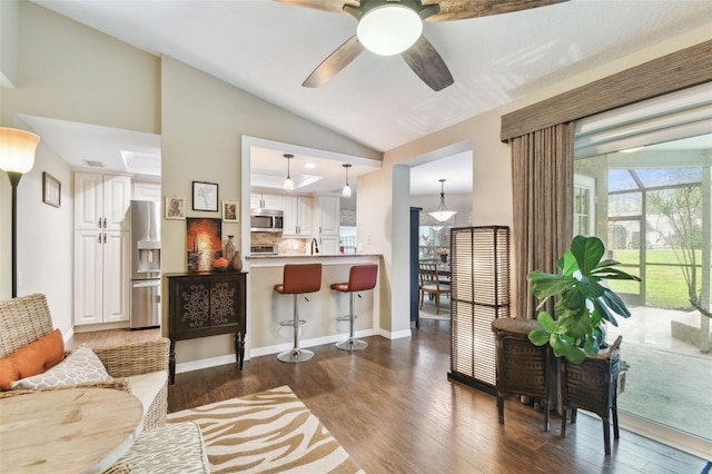 living room featuring lofted ceiling, dark wood-style floors, ceiling fan, and baseboards