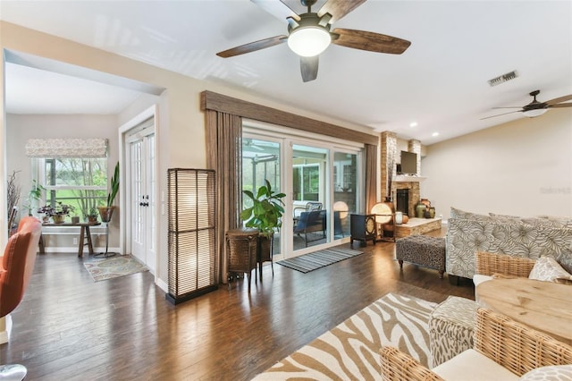 living room featuring dark wood-style floors, baseboards, a fireplace, and visible vents