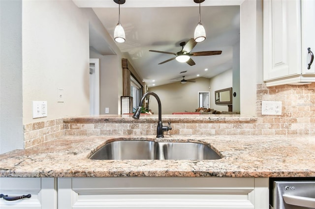 kitchen with hanging light fixtures, a sink, and light stone countertops