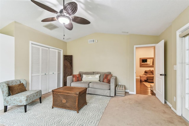 living area featuring vaulted ceiling, a ceiling fan, visible vents, and light colored carpet