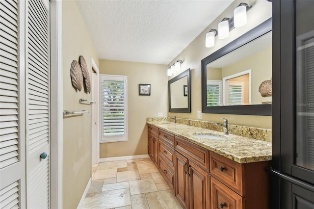 bathroom featuring a sink, stone tile floors, a textured ceiling, and a closet