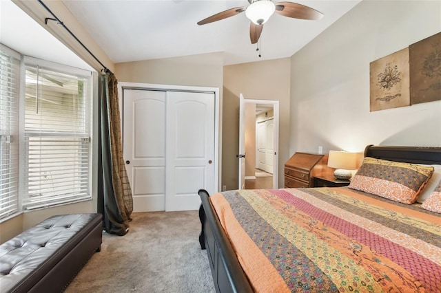 bedroom featuring lofted ceiling, ceiling fan, a closet, and light colored carpet