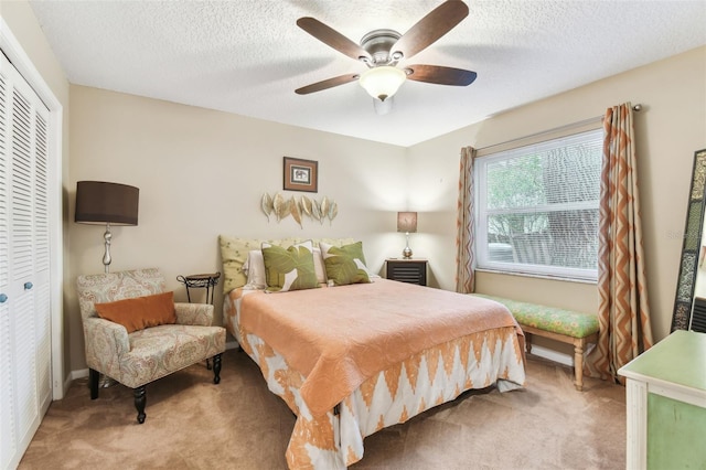 bedroom with light carpet, a closet, a textured ceiling, and a ceiling fan