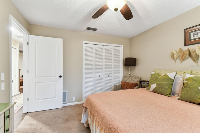 bedroom featuring a textured ceiling, ceiling fan, light colored carpet, visible vents, and a closet