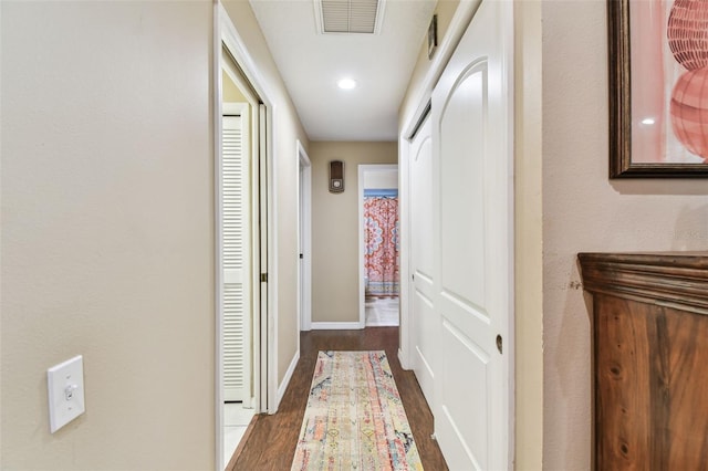 hallway featuring dark wood-style flooring, visible vents, and baseboards