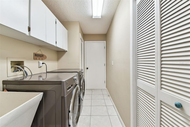 laundry room with cabinet space, light tile patterned floors, baseboards, washing machine and clothes dryer, and a textured ceiling