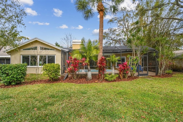 rear view of property with glass enclosure, a lawn, and stucco siding