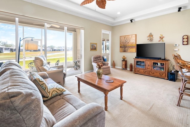 carpeted living room with a tray ceiling and ceiling fan