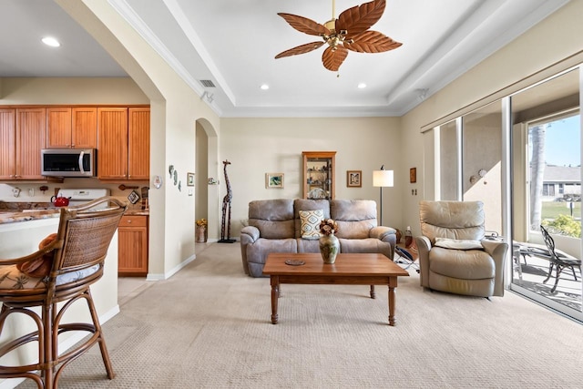 living room with light colored carpet, ceiling fan, and a tray ceiling