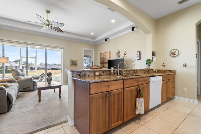 kitchen featuring sink, light tile patterned floors, dishwasher, kitchen peninsula, and dark stone counters