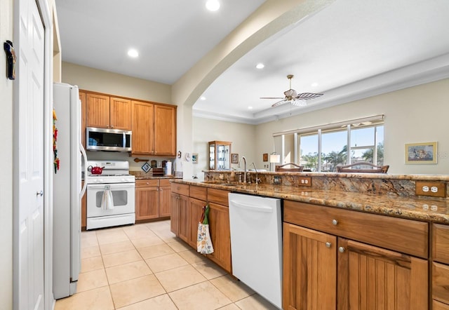 kitchen featuring sink, white appliances, light tile patterned floors, ceiling fan, and light stone countertops