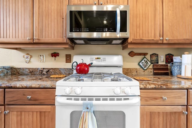 kitchen featuring white range with gas cooktop and stone countertops