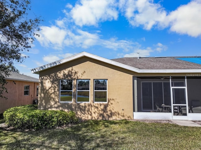 back of property with a sunroom and a lawn