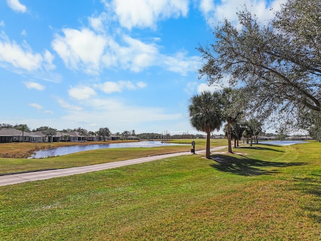 surrounding community with a water view and a lawn