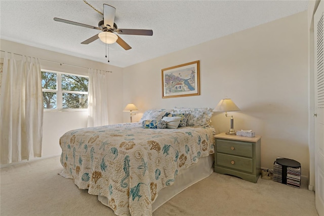 bedroom with ceiling fan, light colored carpet, a textured ceiling, and a closet