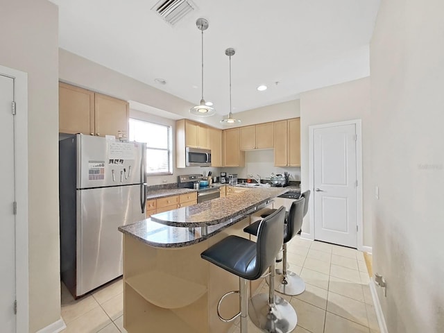 kitchen featuring a kitchen island, hanging light fixtures, light tile patterned floors, stainless steel appliances, and light brown cabinets