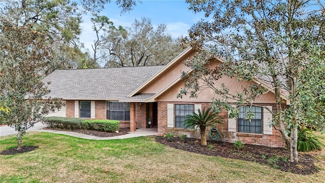 view of front of house with roof with shingles, a front lawn, and brick siding