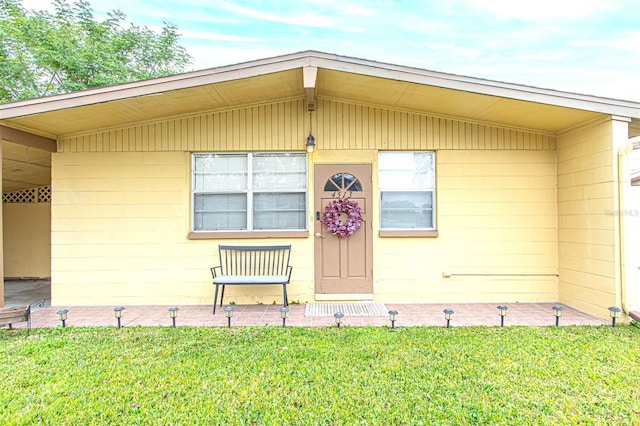 view of exterior entry featuring a yard