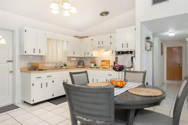 kitchen with lofted ceiling, oven, light tile patterned floors, and white cabinets