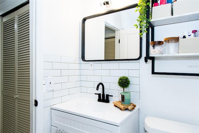 bathroom with vanity, backsplash, and toilet