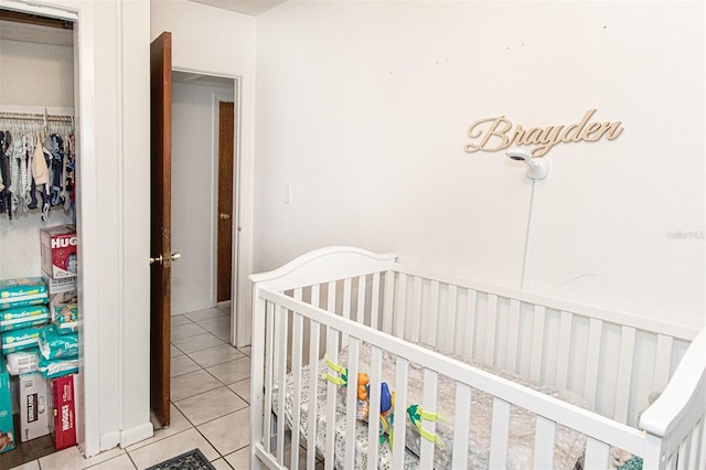 bedroom featuring a crib, a closet, and light tile patterned flooring