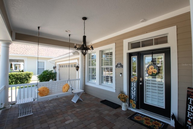 view of exterior entry featuring a garage and covered porch