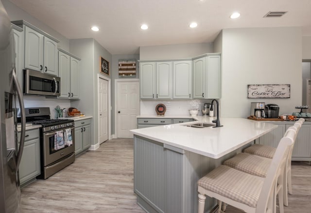 kitchen featuring sink, light hardwood / wood-style flooring, a breakfast bar, stainless steel appliances, and kitchen peninsula