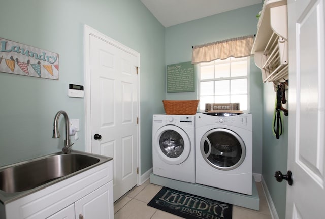 washroom with cabinets, washing machine and clothes dryer, sink, and light tile patterned floors